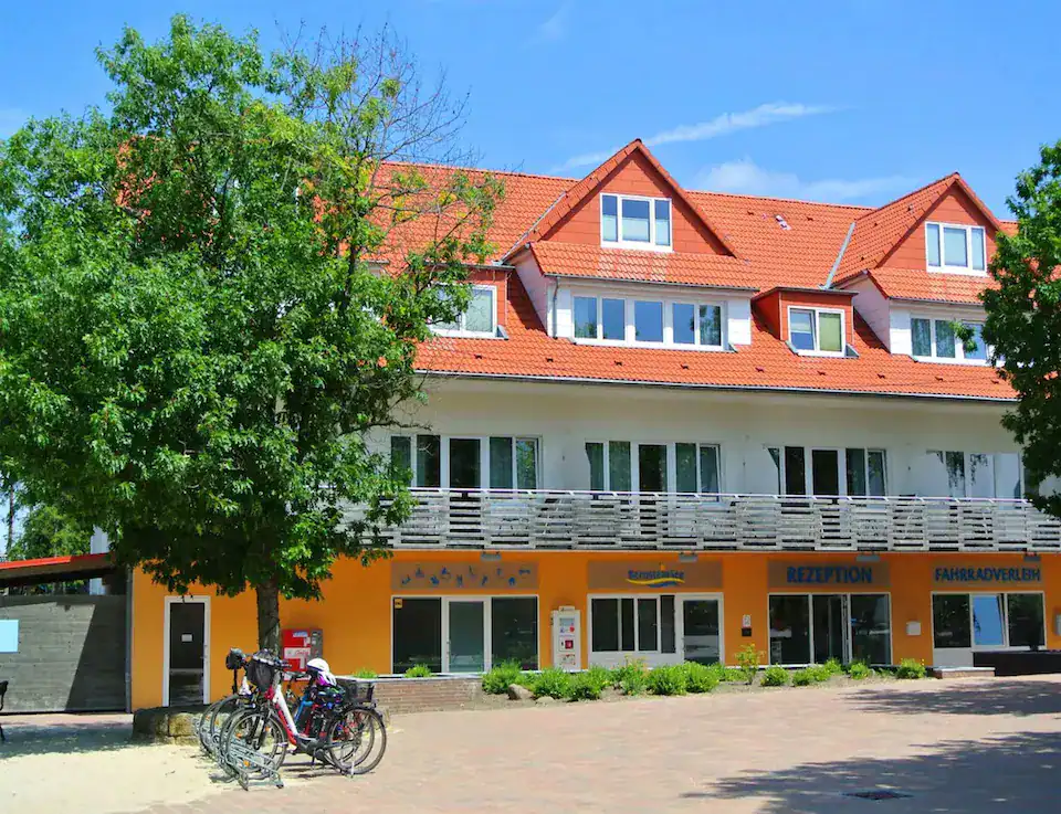 Colorful hotel building with red roof and bicycles in front under blue sky.